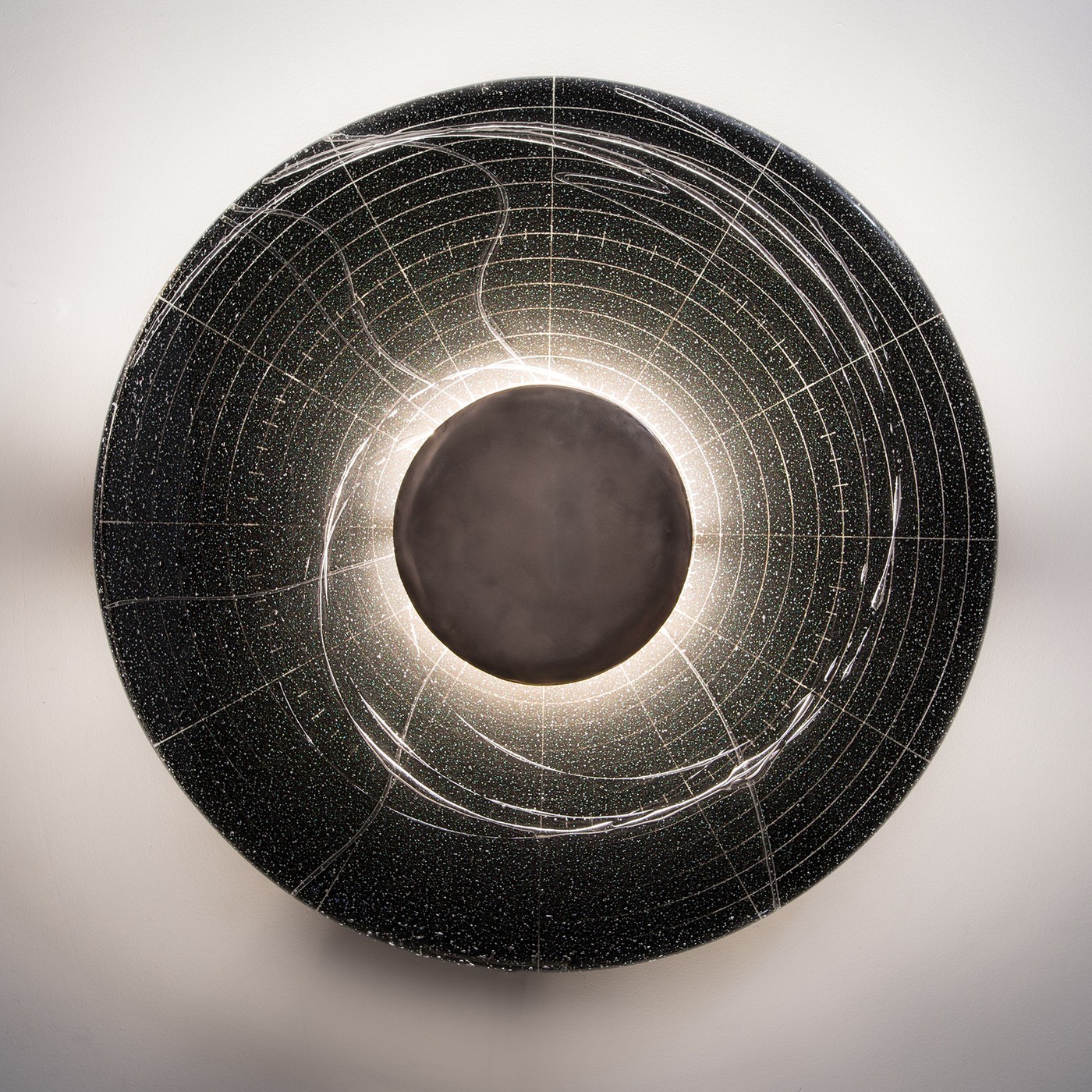 Annular, a round wall sconce glowing at its center like an eclipse